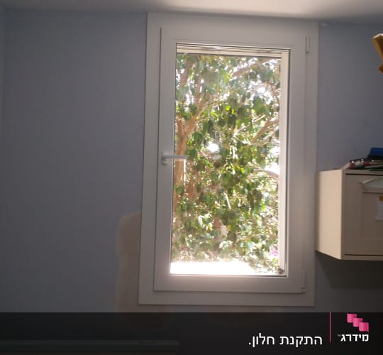 חלון עם קיר צבוע חלקית בתהליך שיפוץ
